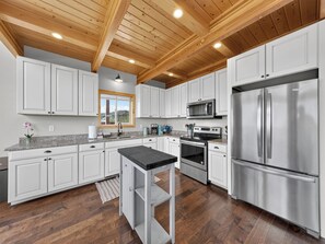 A modern kitchen with white cabinets, stainless steel appliances, and a wooden ceiling. - Aspen Outpost - Best Views in Brian Head! (Brian Head)