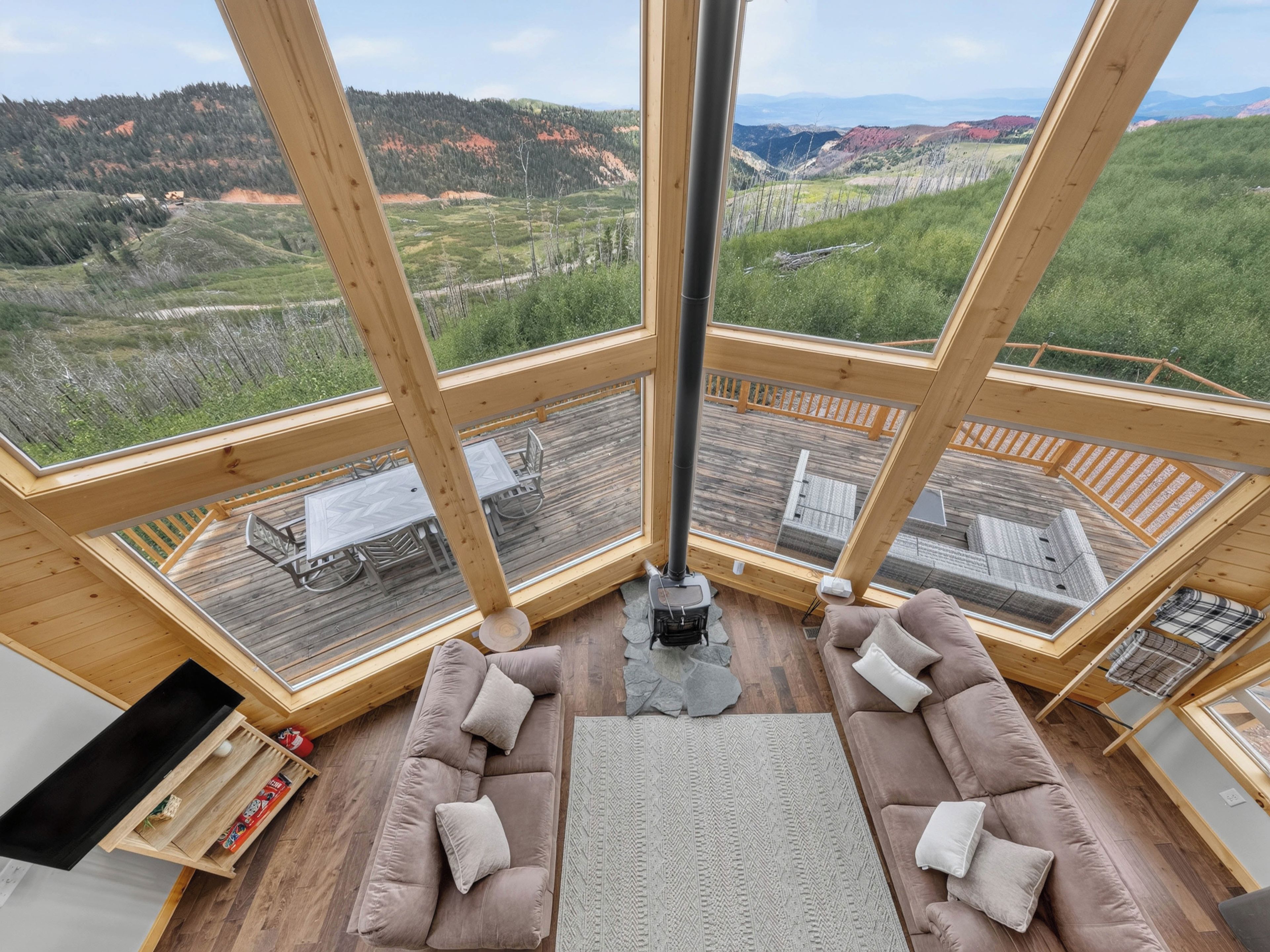 A high-ceilinged room with a large window overlooking a scenic landscape, a fireplace, and a cozy seating area.