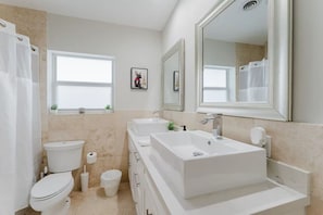Ein modernes Badezimmer mit Toilette, Bidet und einem großen Waschbecken mit Spiegel darüber.