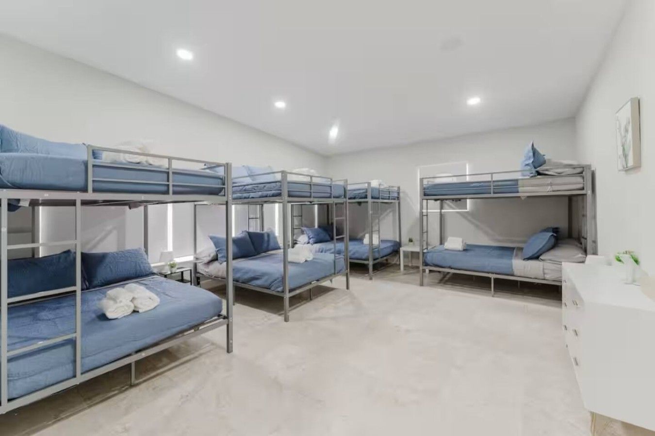 Une chambre de dortoir avec des lits superposés, une petite table et une armoire blanche.