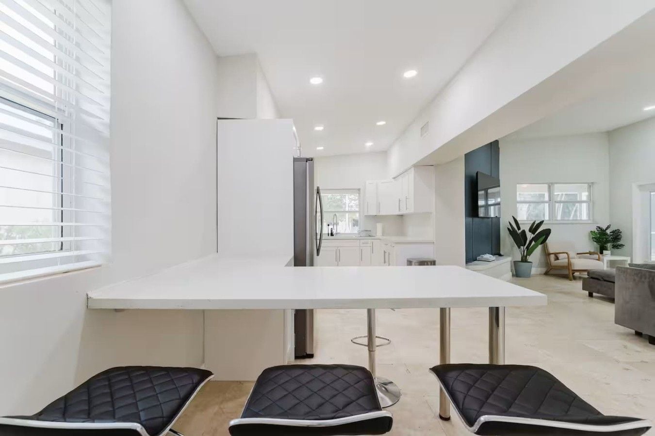 A modern kitchen with a white countertop and black chairs.