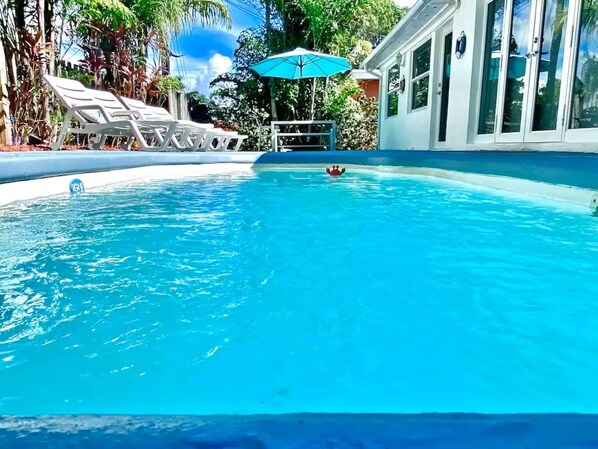 A clear blue swimming pool with lounge chairs and a small umbrella. - 5BD House - Pool+BBQ+King beds | 3 min to beach (Hollywood)