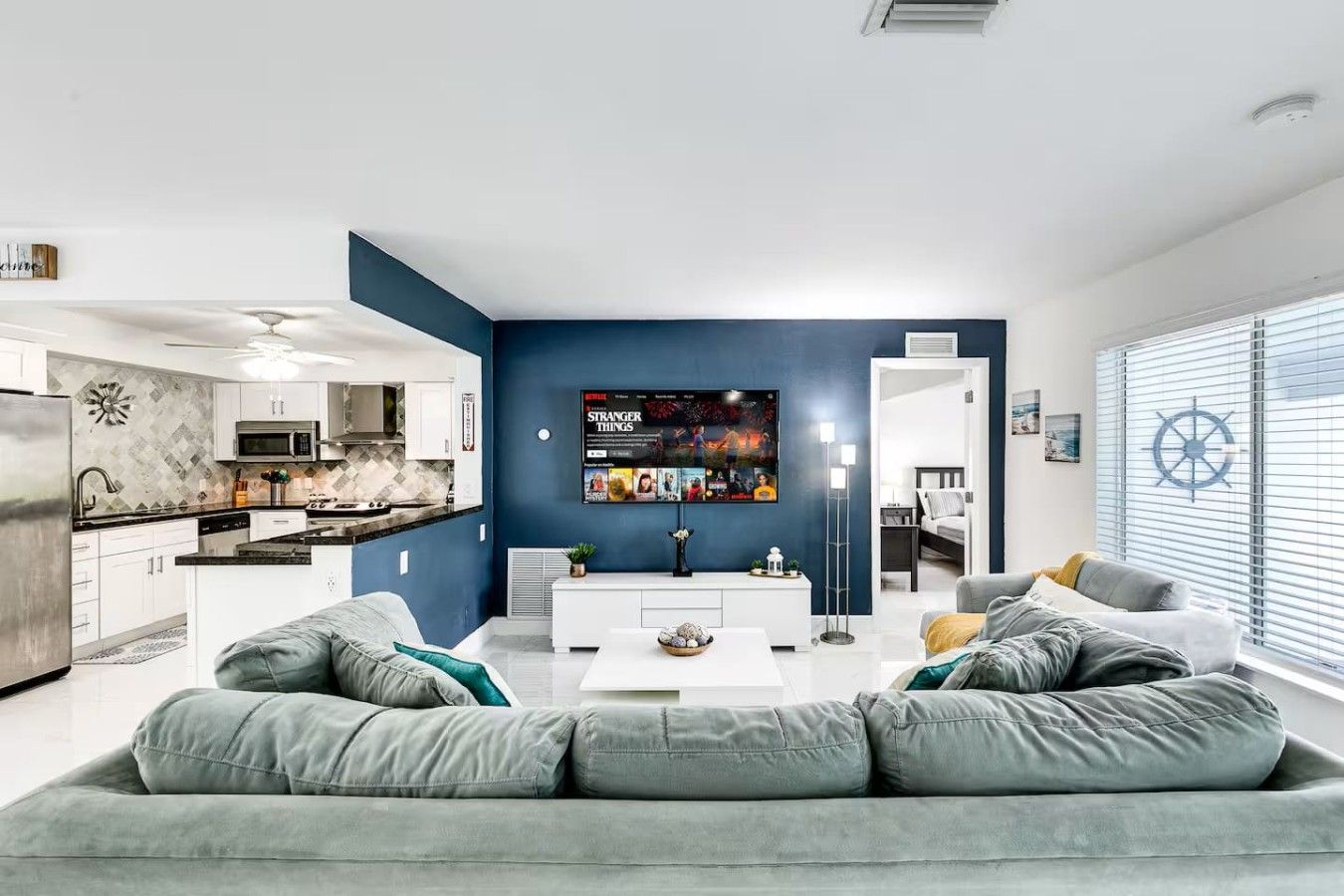 A modern living room with a grey sofa, a coffee table, and a TV mounted on the wall.