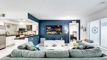 A modern living room with a grey sofa, a coffee table, and a TV mounted on the wall.