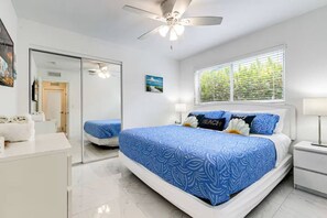 A hotel room with a large bed, a ceiling fan, a window with blinds, and a mirror. - 5BD House - Pool+BBQ+King beds | 3 min to beach (Hollywood)