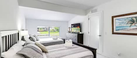 A bedroom with a bed, a nightstand, a dresser, a television, and a painting.