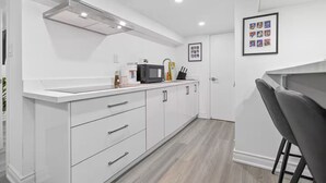 A modern kitchen with white cabinetry, a microwave, and a coffee maker on the counter. - Private 2BR Unit w/ Kitchen, WiFi • Sleeps 4 (Toronto)