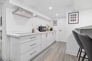 Cocina moderna con armarios blancos, un microondas y una cafetera sobre la encimera.