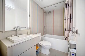 Un bagno moderno con lavandino, water e vasca da bagno bianchi.