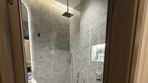 A modern bathroom with a shower, toilet, and a glass door leading to another room. - VATERRA House Lagos (Lekki)