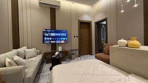 A modern hotel room with a flat-screen TV, a sofa, a bed, and a small table. - VATERRA House Lagos (Lekki)