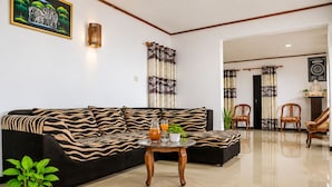 A modern living room with a black sofa, a round coffee table, and a potted plant. - VATERRA House Lagos (Lekki)