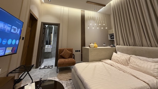A modern hotel room with a large bed, a television, a desk, and a bathroom visible through an open door. - VATERRA House Lagos (Lekki)