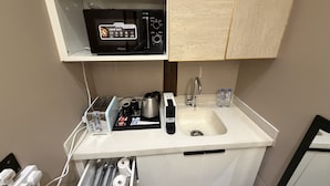 A kitchenette with a microwave, toaster, kettle, and a small sink. - VATERRA House Lagos (Lekki)