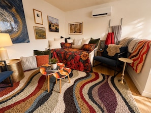 Ein gemütliches Wohnzimmer mit einer Couch, einem Couchtisch und einem gemusterten Teppich.