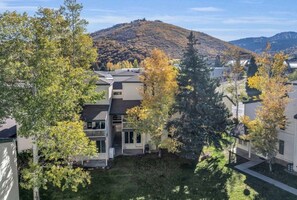 Zona residencial amb cases, un turó al fons i arbres amb fulles d'octubre.