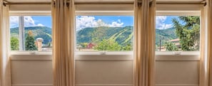 A window with a view of a mountainous landscape, a red building, and a tree. - Retro Park City Condo, 3BR + Loft, Near Major Ski Resorts (Park City)