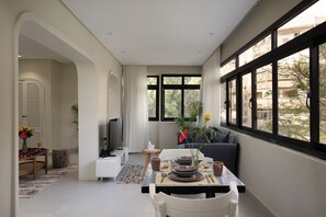 A modern dining area with a table set for two, a television, and a view of the outdoors through large windows. - Cozy Stay at bait assel by spacey  (cairo)
