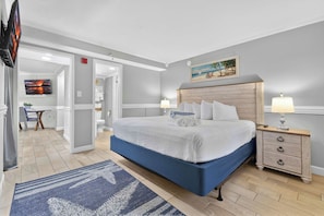 A bedroom with a bed, bedside tables, a painting, and a view of the bathroom. - Monterey Bay 1437 - Ocean Front (Myrtle Beach)