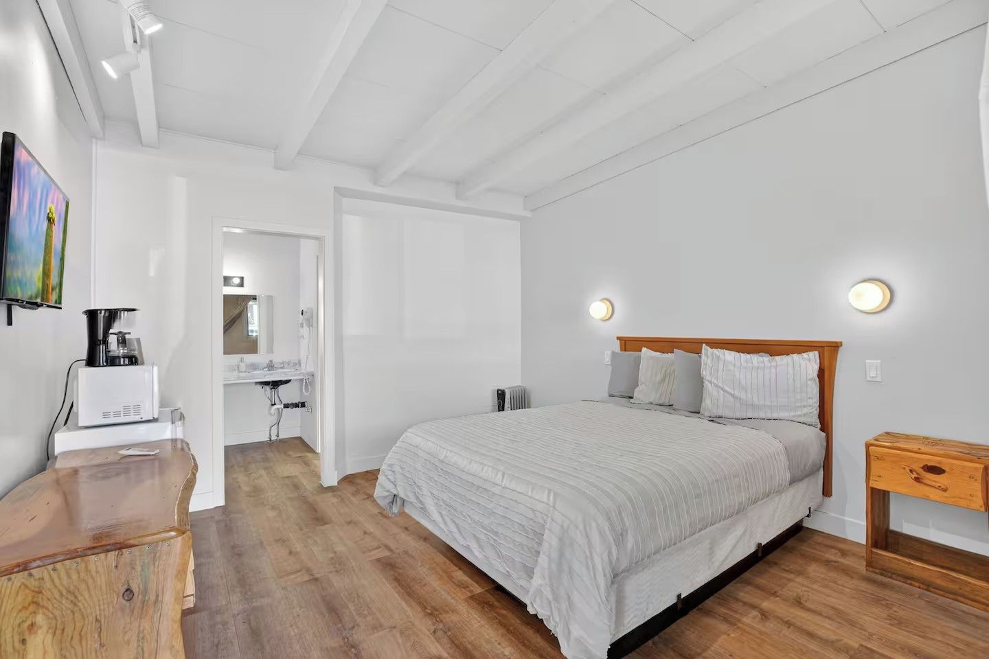A bedroom with a bed, bedside table, and a wooden nightstand.