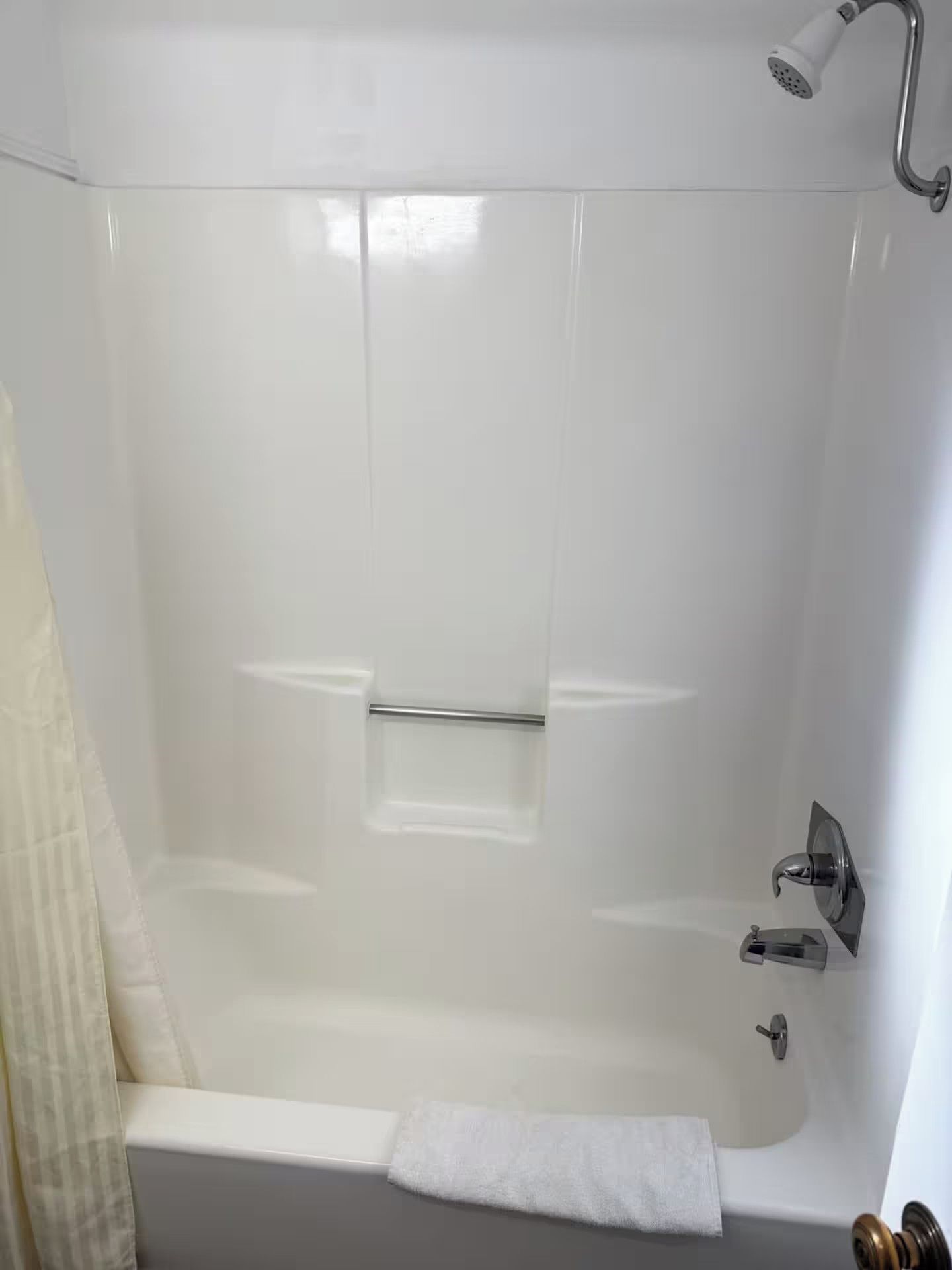 Una bañera con ducha y un perchero para toallas.