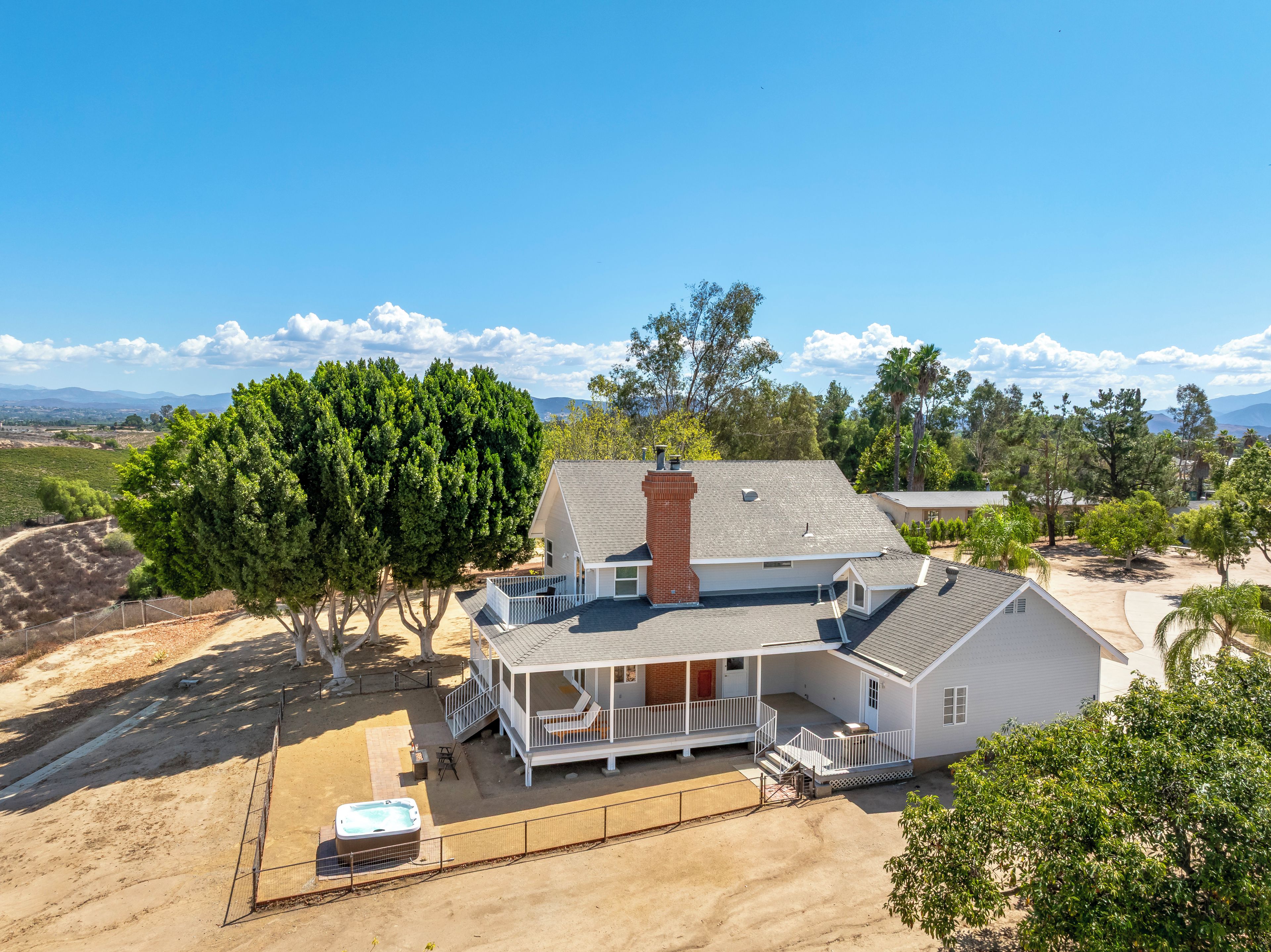 A single-story house with a covered porch, a hot tub, and a fenced yard.
