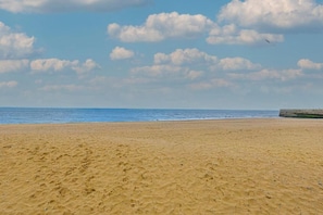 Een zandstrand met een heldere lucht en een verre zeewering.