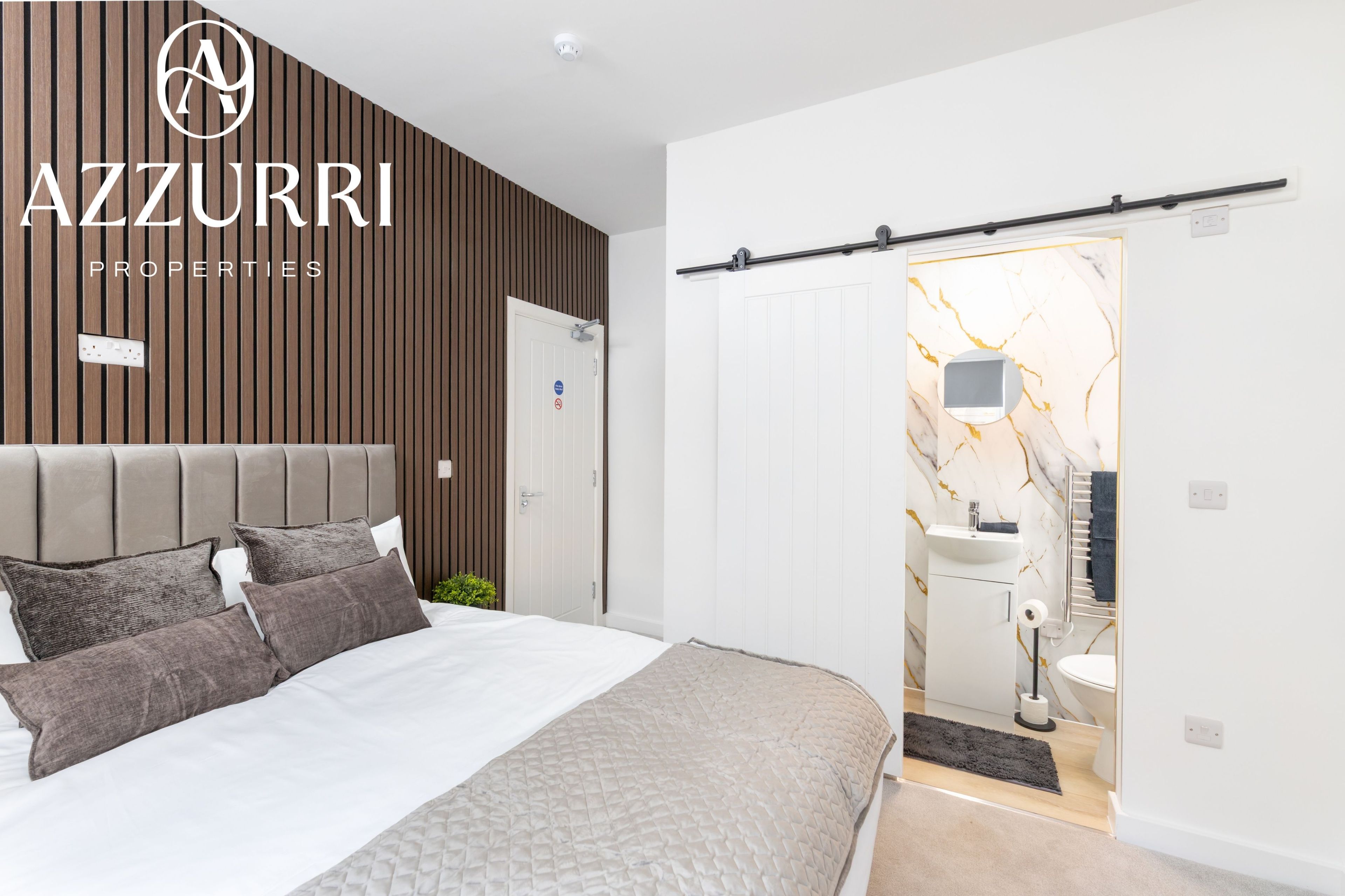 A modern bedroom with a bed, a headboard, and a sliding door leading to a bathroom.