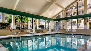 An indoor swimming pool with clear water, surrounded by lounge chairs and a view of a building with balconies. - Gatlinburg Town Village  (Gatlinburg)