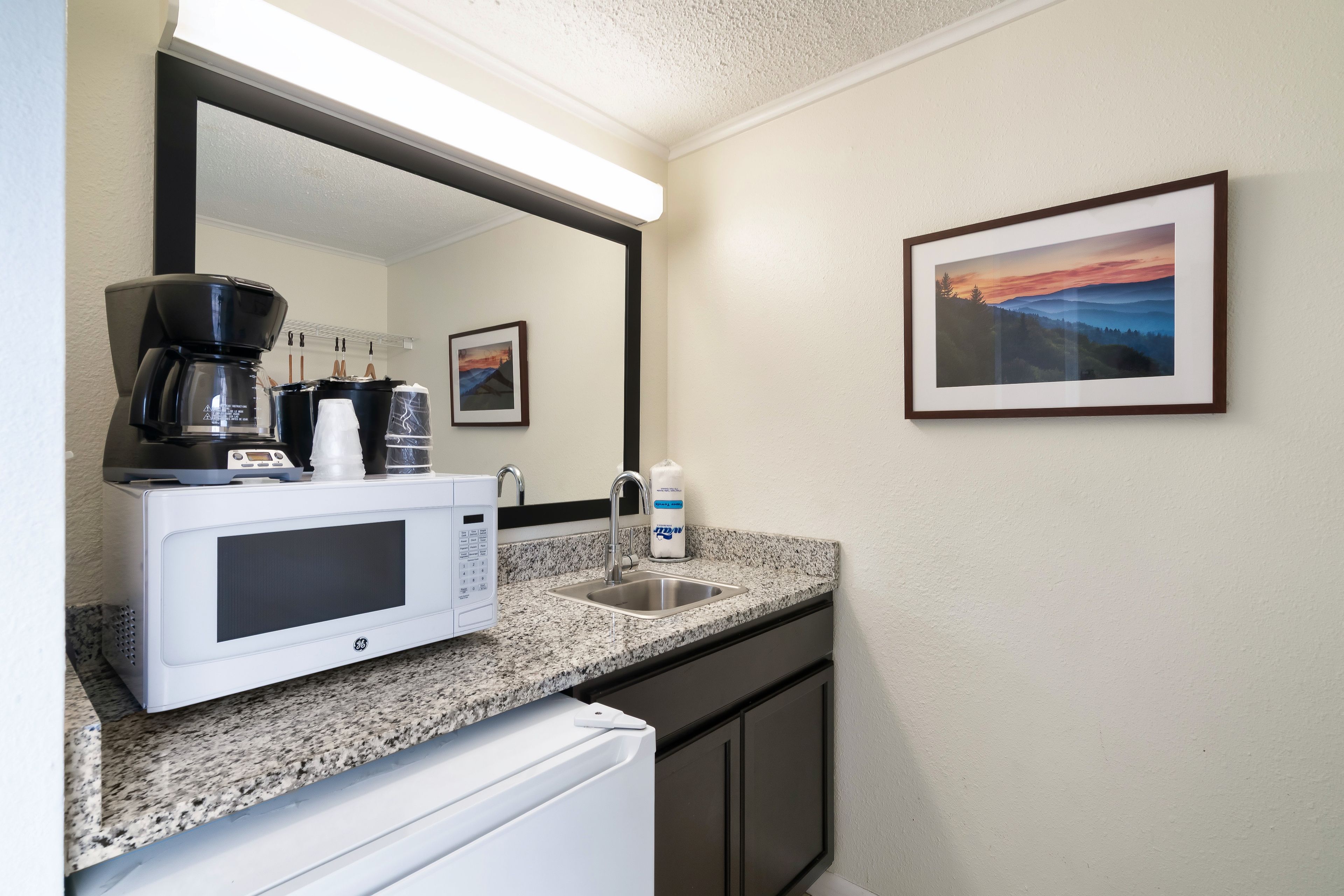 A kitchenette with a microwave, coffee maker, and sink.