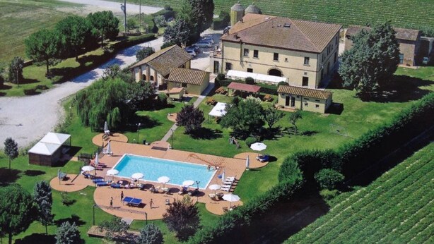 Una extensa propiedad con piscina, mobiliario exterior y un viñedo al fondo.