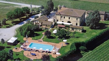 Una extensa propiedad con piscina, mobiliario exterior y un viñedo al fondo.