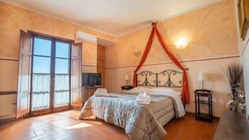 Una habitación de hotel con cama, televisor, ventana con cortinas, aire acondicionado instalado en la pared y piso de baldosas.