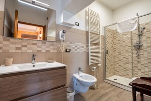 A modern bathroom with a dual sink vanity, a bidet, a glass shower enclosure, and a towel rack. - Case Vacanze I Chiari - 40 Camera doppia (Montepulciano)