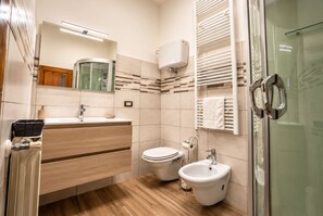 Un baño moderno con tocador de madera, inodoro, bidé y cabina de ducha de vidrio.