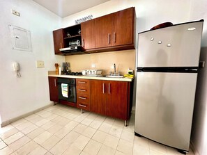 A kitchen with wooden cabinets, a stainless steel refrigerator, a built-in oven, and a toaster. - by Calamari.Homes - Centenario Casa 102 - Old City (Cartagena de Indias)