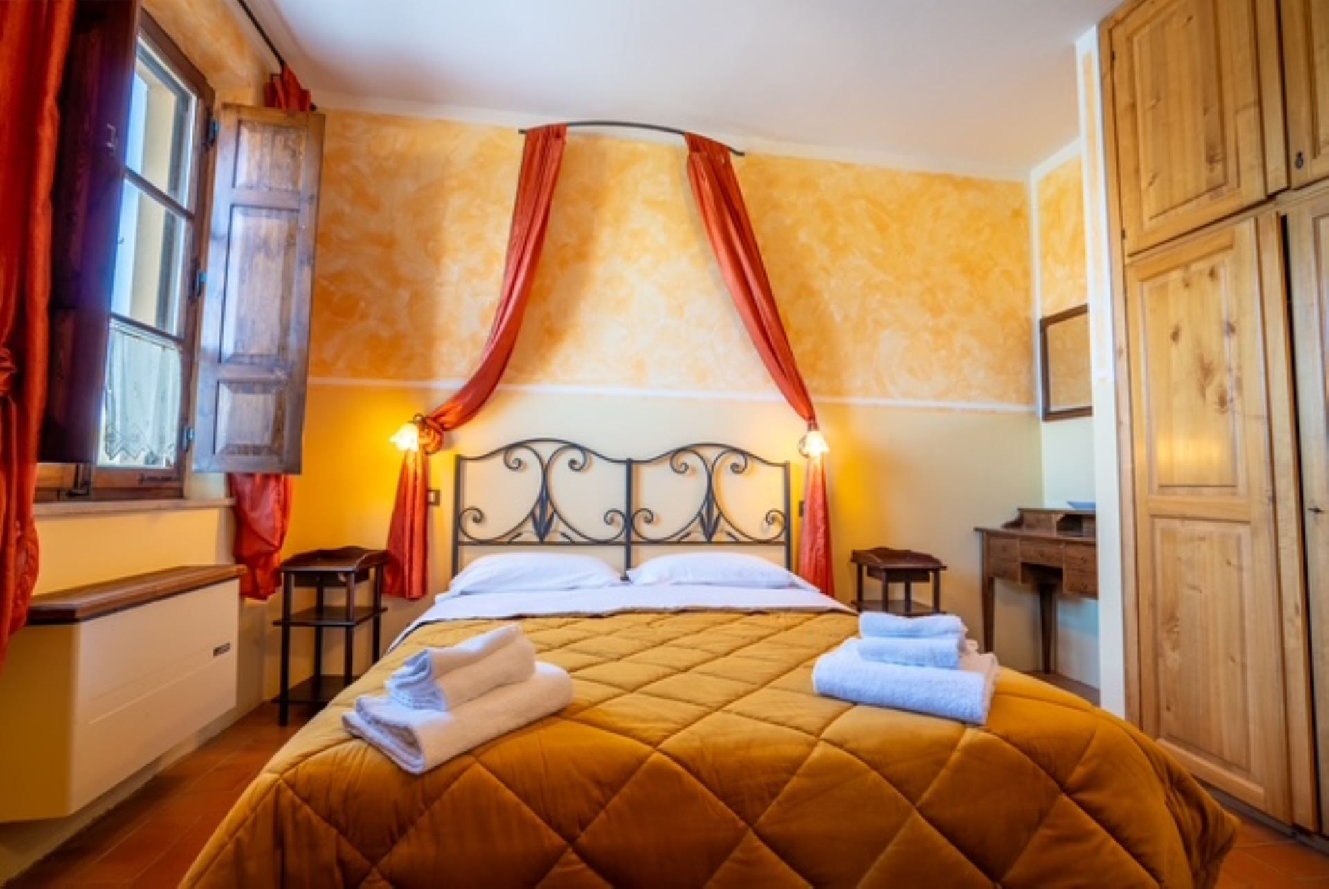 Una habitación de hotel con cama, cortinas, mesita de noche y armario.