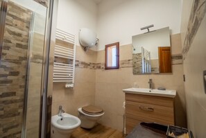 Un baño con ducha, inodoro, bidé, tocador y espejo.