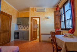 Una cocina con armarios de madera, salpicadero de azulejos y una ventana con cortinas.