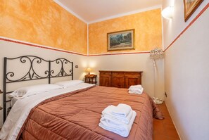 Una habitación de hotel con una cama, una mesita de noche, una lámpara y un cuadro en la pared.