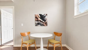 Ein Essbereich mit einem runden Tisch und zwei Stühlen, einem Gemälde an der Wand und einer Tür im Hintergrund.
