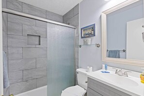 Un bagno con doccia, WC, lavandino e specchio.