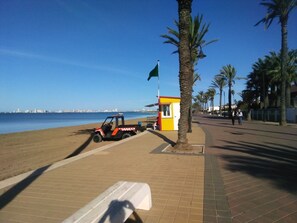 Cena à beira-mar com um posto de salva-vidas, um veículo estacionado e uma vista ampla do oceano.