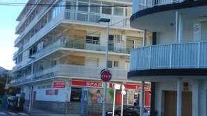 Ein mehrstöckiges Gebäude mit Balkonen, einem Stoppschild und einem Geschäft mit Beschilderung.
