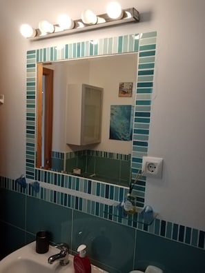 Ein Badezimmer mit Spiegel, Waschbecken und Handtuchhalter.