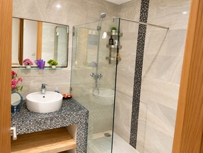 A modern bathroom with a glass-enclosed shower, a white sink, and a mirror above it. - Beautiful 2-bedroom Apartment With Pool View Mohammedia (El Mansouria)