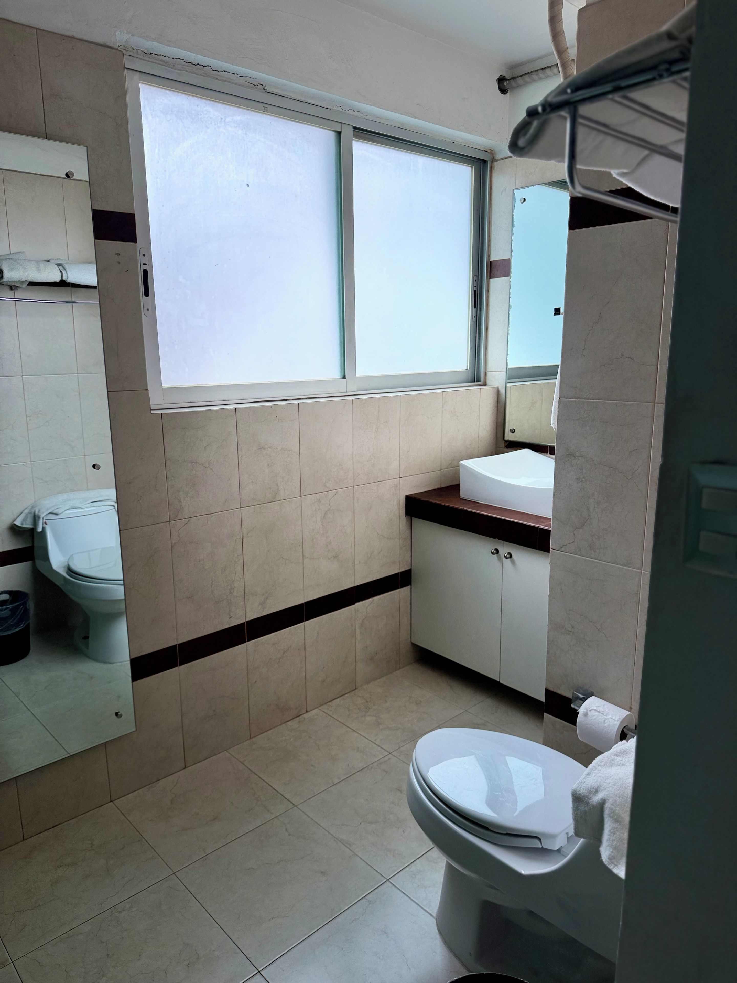 Un baño con inodoro, lavamanos y ventana.