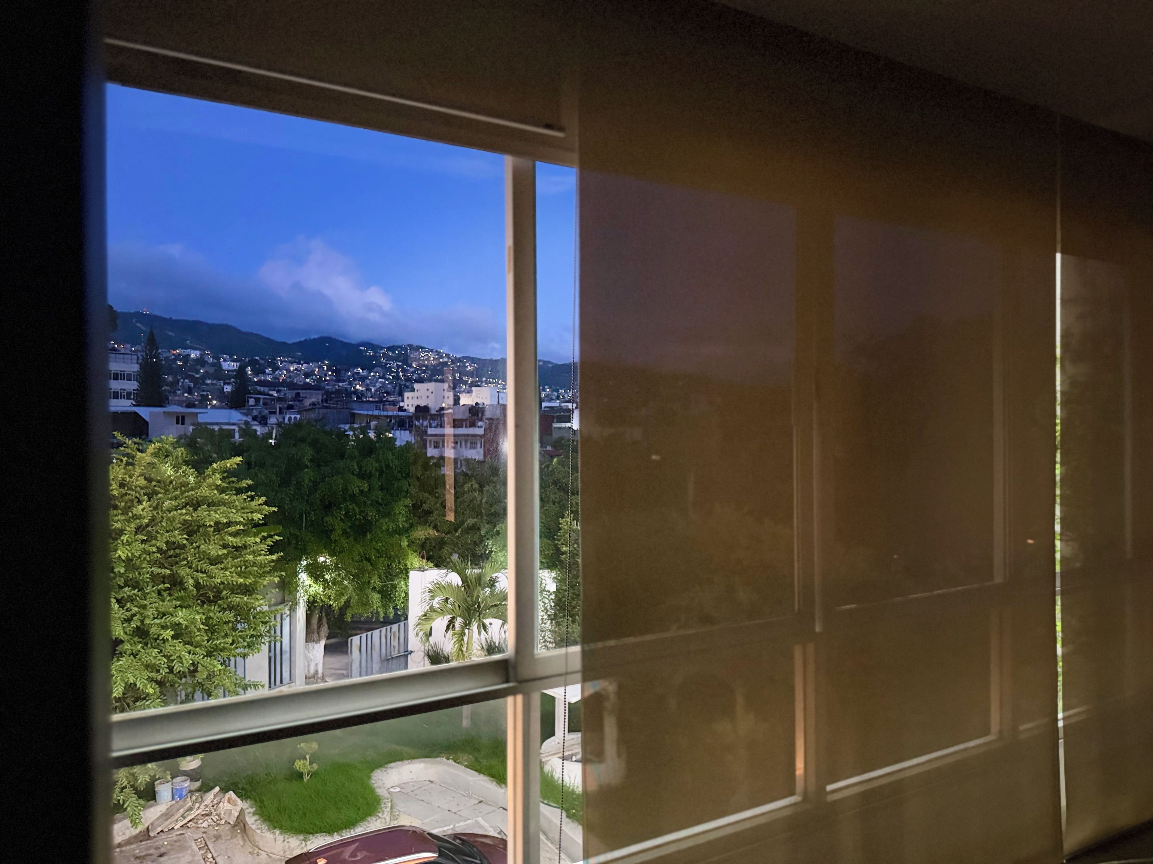 Vista desde una ventana de un paisaje urbano con edificios y áreas verdes.