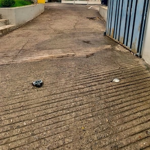 A concrete pathway leading to a building entrance with a metal fence on one side.