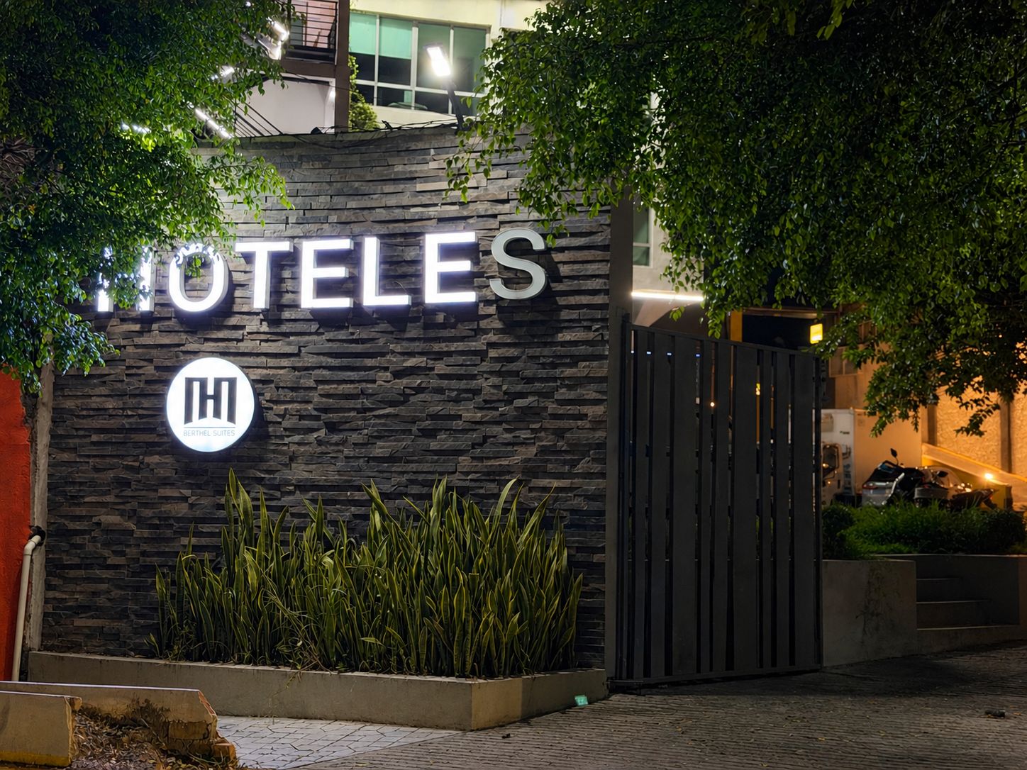 A hotel entrance with a stone facade, a prominent sign, and a gated driveway.